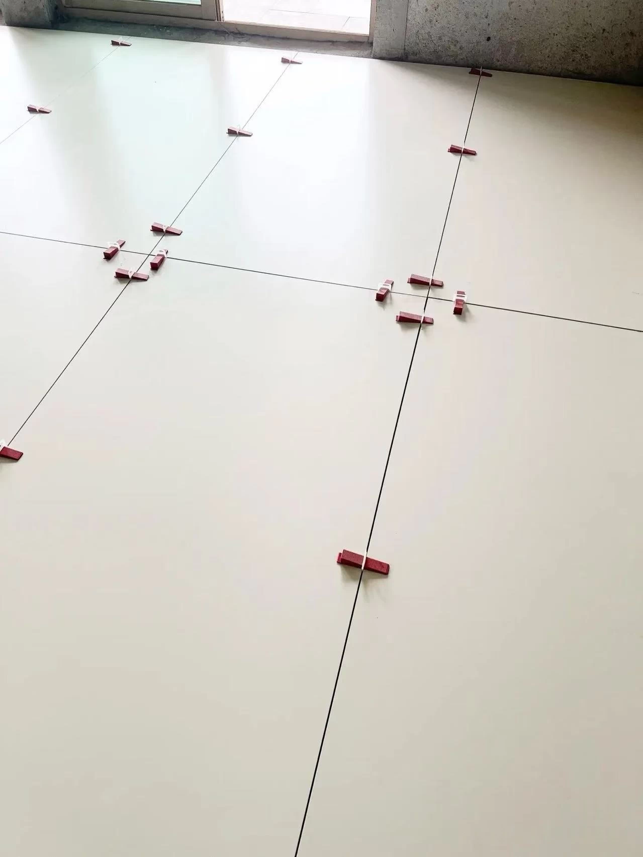 Close view of large tiles during installation using spacers—honed porcelain tile with tight grout lines