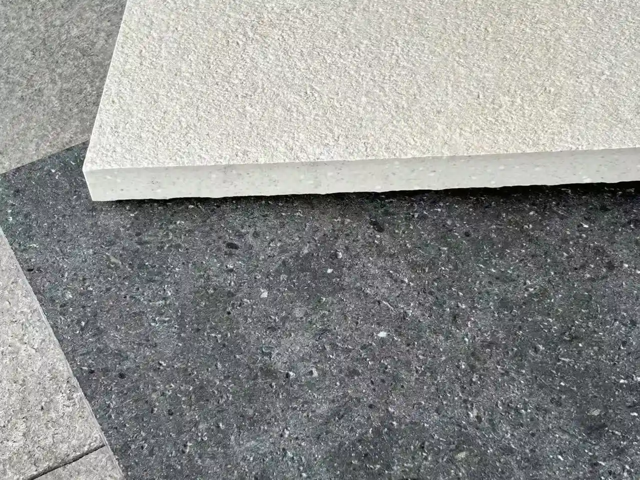 Outdoor-Ready Textured Floor Tile | China Supplier Beige textured porcelain floor tile on dark terrazzo-look background, outdoor-ready surface