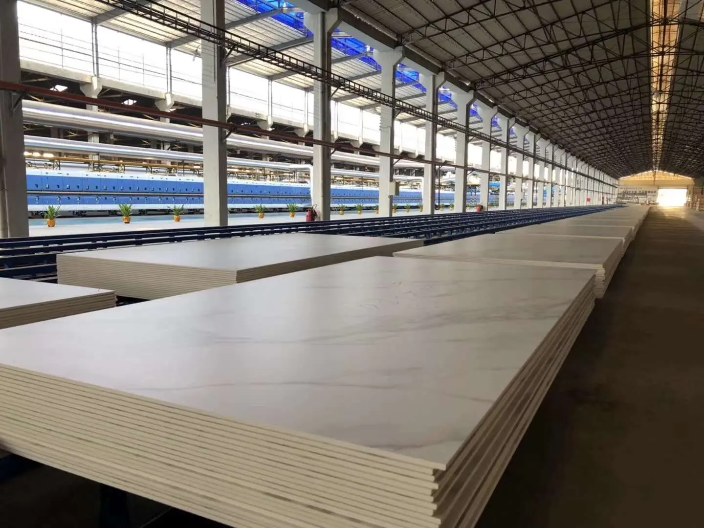 Foshan Porcelain Tile Factory Large Slab Production Foshan porcelain tile factory with large-format slab production and stacked sintered stone panels inside a modern workshop