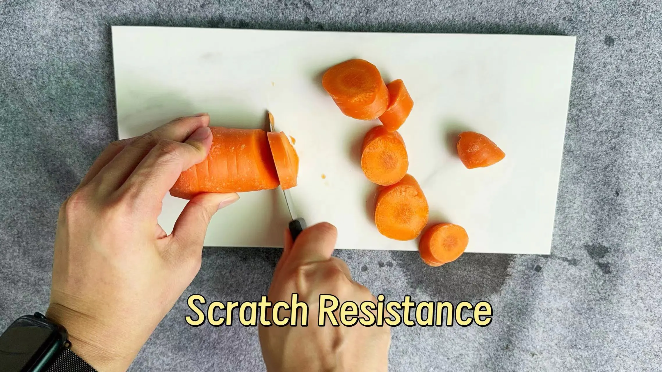 Knife cutting carrot on sintered stone slab to demonstrate superior scratch resistance surface