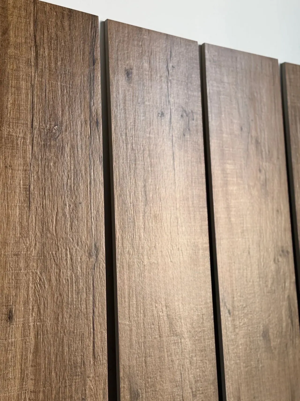 Close-up texture of rustic brown wood tile planks manufactured by Kingsun in China for heavy-traffic flooring.